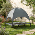 Lit-camp-chien-auvent-120-cm, en tissu oxford 100% imperméable et maille respirante et structure en acier inoxydable, avec son dôme parasol amovible anti uv et anti pluie, polyvalent pour une utilisation interieur et exterieur, surélevé avec 4 pieds et deux barres transversales au milieu et patin anti rayure pour une stabilité pour chiot et chien de petite à moyenne taille jusqu'à 30 kilos-gros plan sur le lit de camp avec son dôme parasol installé de couleur gris et noir dans le jardin de la maison 