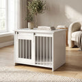 Meuble-niche-pour-chien-petit et moyenne taille-cage-80 cm en bois blanc et porte avant coulissante avec roulettes solides et silencieuses en cadre en bois et barreaux blancs en acier robuste, meuble rectangulaire et cage au design moderne, imperméable et robuste  pour chiot et chien de 0 à 15 kg-gros plan sur le meuble niche au style épuré scandinave avec sa porte coulissante fermée et décoration sur le meuble lifestyle qui apporte un touche de charme dans le salon de la maison