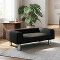 Mini-canapé-pour-chien-chiot-design-velours noir, surélevé avec 4 pieds en acier inoxydable cylindriques, rembourrage 100% coton haute densité épais pour les accoudoirs et le dossier-assise avec matelas en mousse de forme rectangulaire moderne, résistant aux griffes, structure en bois massif naturel-design moderne en couleur noir dans le salon de la maison