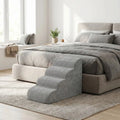 Petit-escalier-pour-chien-dehoussable-en-mousse haute résilience qui atténue la pressions sur  ses articulations, résistant et doux pour ses coussinets, déhoussable, imperméable et lavable en machine de couleur gris pour chien de petite taille, polyvalent compact et transportable-un escalier gris placé contre le lit du propriétaire du chien dans la chmabre de la maison