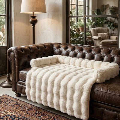 Protection-canape-chien-lit-antiderapant avec traversin entourant sur 3 côté, en fausse fourrure rembourrage 100% coton haute densité, polyvalent pour le sol, canapé, protège lit, portège siège voiture, tapis de cage, pliable, léger et portable pour petit à chien moyenne taille-dimensions 75x75 cm-gros plan sur le protège canapé pour chien en fausse fourrure douce de couleur blanc crème sur le canapé en cuir capitonné dans le salon de la maison