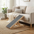 Rampe-pour-chien-pliable, en bois massif robuste de pin et surface adaptable en moquette douce et antidérapante pour un accès sécurisé et facile au meubles, canapé, lit de la maison ou en transport en déplacement, en voiture pour la montée et la descente du chien en toute autonomie et sécurité-photo de la rampe inclinée contre le canapé du salon, idéal pour les races aux articulations fragiles, âgés, atteint de dysplasie, en croissance ou convalescence
