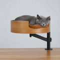 Lit design pour chat en bois fixé à une table avec coussin doux marron et chat gris allongé