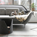 Lit en feutre fait main Oscar et Plume pour chats, confortable et élégant, placé près d'un canapé