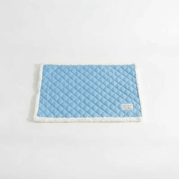 Tapis réversible pour chat et chien bleu avec bordure blanche moelleuse sur canapé blanc