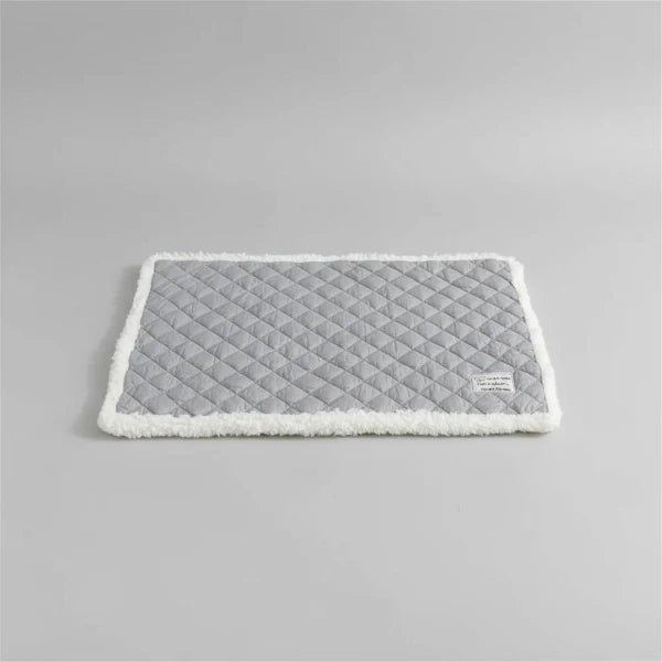 Tapis réversible pour chat et chien gris avec bord en fausse fourrure sur canapé blanc